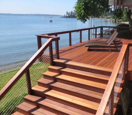 Batu-cable-rail-deck-and-stairs A coastline deck built from batu tropical hardwood. a 8 foot wide stairway rises from the yard. The railing has Ultra-tec cables and a drink rail. Lounge chairs face the sea.