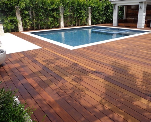 Batu-Pool-deck-stained A pool deck sits flush with the pool it sits around. The decking is batu 1x6 and is stained, the colors show deep red-tones.
