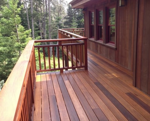 Dark-Red-Meranti-Philippine-Mahogany-Deck A cabin styled home in a woodland setting has wood siding and a deck built with DRM, dark red meranti, decking