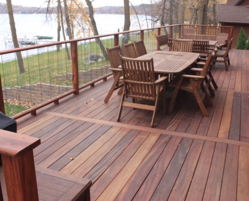 Tigerwood-Deck-on-River-with-hogwire A tigerwood deck with a glass slat railing looks over lake Washington. Divider boards separate the runs of decking.