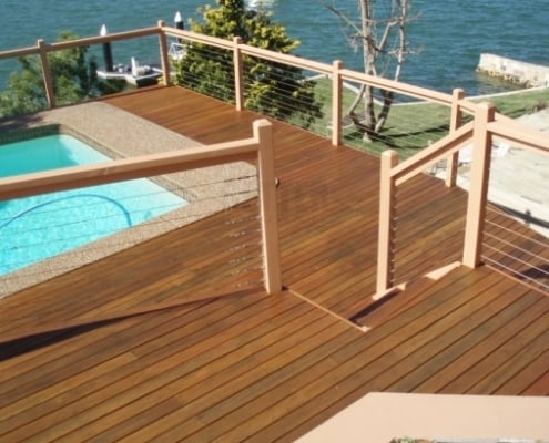 batu-coastal-deck a batu pool deck surrounded by cable rail looks over a coastal view, a boat sits offshore.